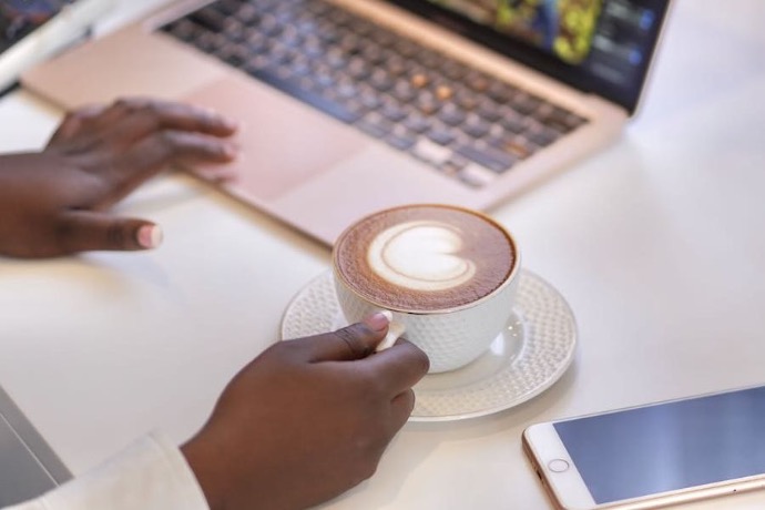 African Man hands working on mac book while drinking cappuccino